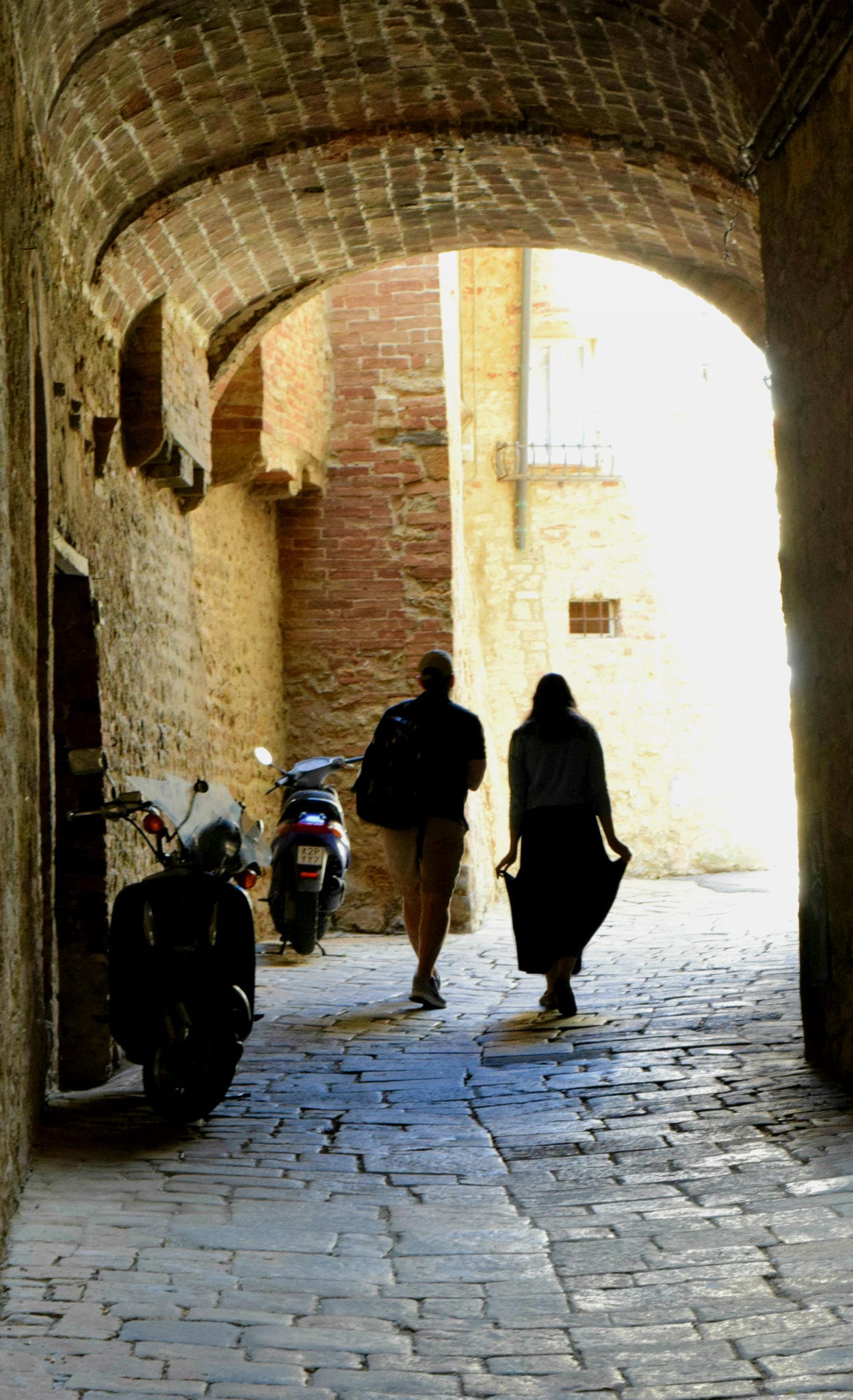 kate storm and her dad walking through an archway on a trip to volterra italy